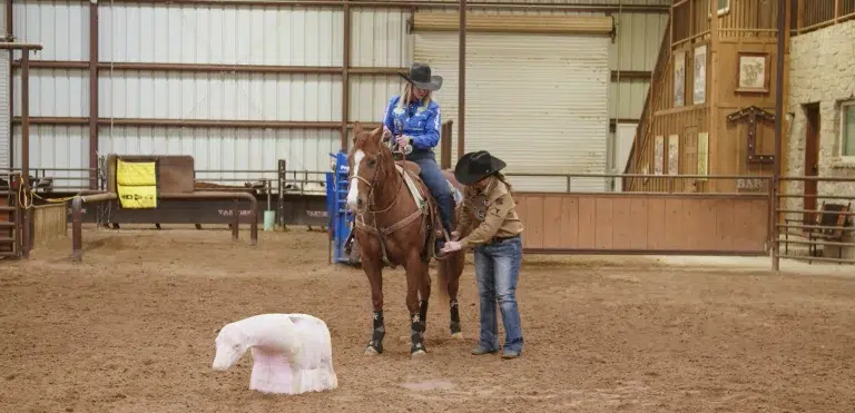 Lari Dee Guy demonstrates leg positioning by guiding the leg of a mounted rider