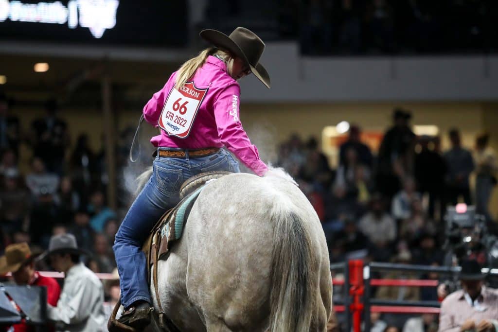 Kendal Pierson petting her gray horse Smoke at the 2022 Canadian Finals Rodeo. 